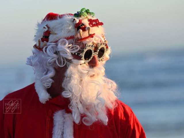 Santa Claus wearing festive sunglasses and a Christmas hat outdoors during winter.