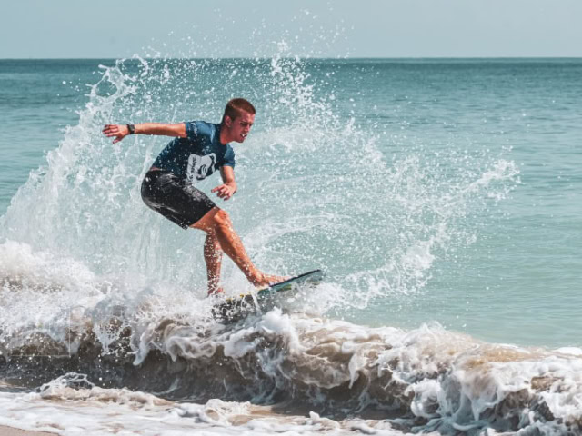 A young man surfing on the ocean waves at JJ Photo Gallery.